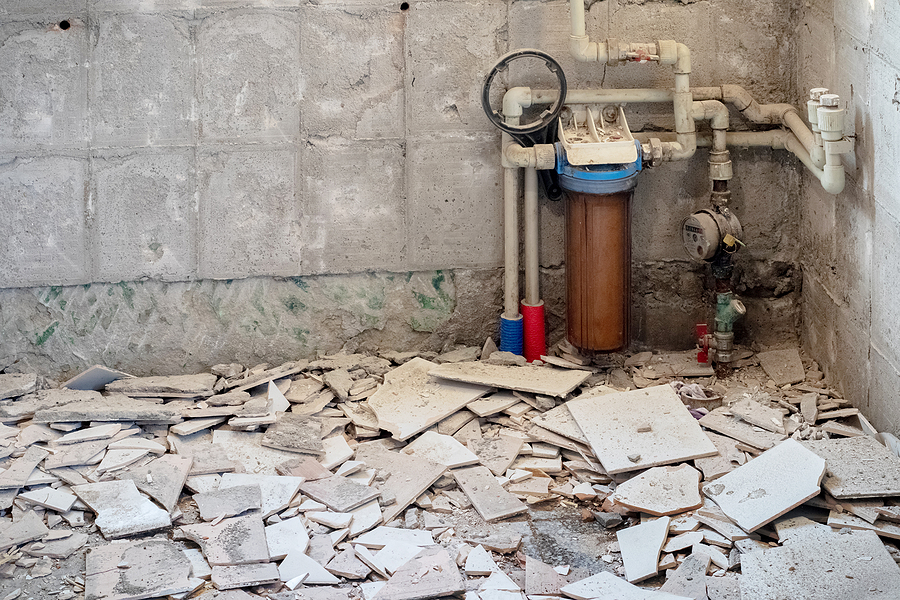 Renovation in an old room, dismantled floor tiles, concrete walls, plumbing elements, construction debris